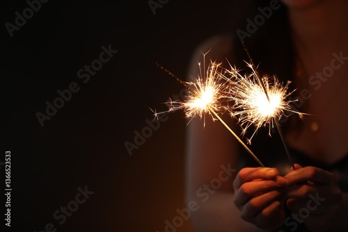 Obraz na płótnie Woman with bright burning sparklers on dark background, closeup. Space for text w salonie