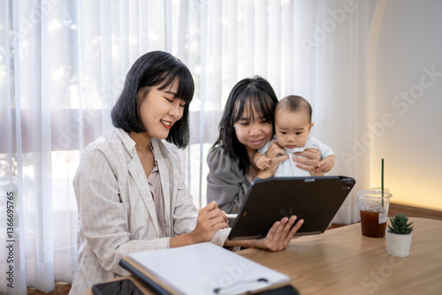 A woman is sitting at a table with a baby and a laptop