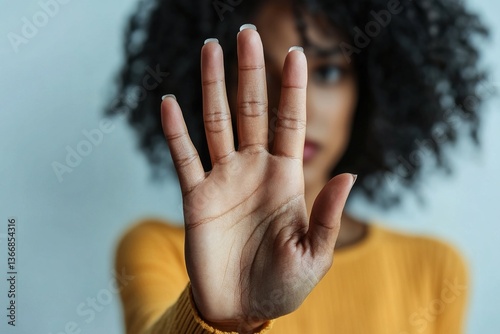 Woman holds up her hand in stop gesture, as symbol of resistance, defiance, or protest, struggling social issues, against racial discrimination, sexism, harassment, and gender-based violence, close up