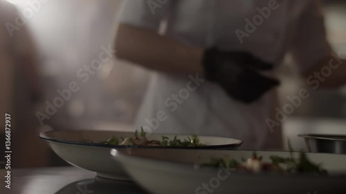 Unrecognizable chef pouring sauce over plated dish