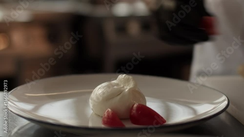 Unrecognizable chef serving burrata with tomato slices in plate