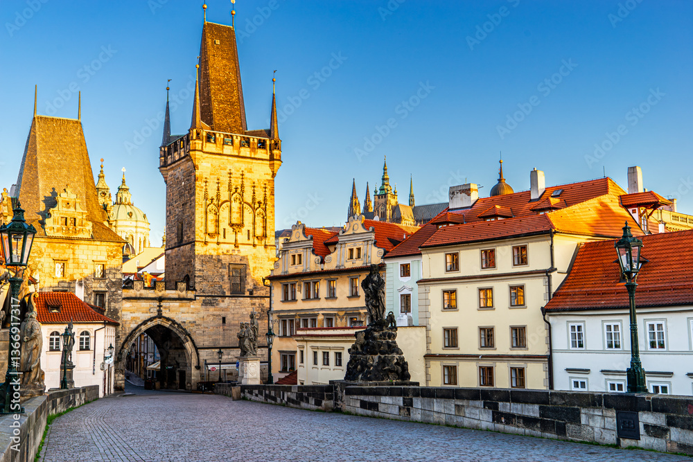 Fototapeta premium Prague, Czech Republic, in daylight, presents a picturesque scene from the Charles Bridge, looking towards the majestic Lesser Town Bridge Towers, with historic statues standing guard and colorful arc