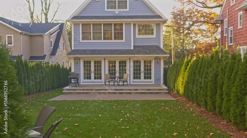 camera pan across residential home showing a well maintained back yard with patio furniture, green grass and grill.