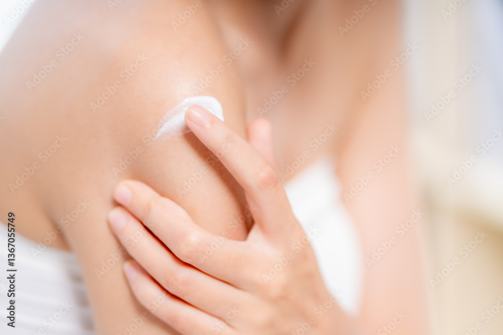 Fototapeta premium Moisturizing skin care is essential for maintaining healthy skin. This captures person applying cream to their shoulder, highlighting importance of skin care in daily routines