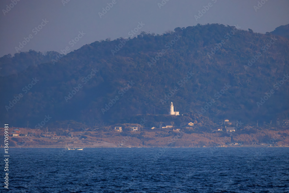 Fototapeta premium 夕日に染まる房総半島。 白い灯台や漁船も見える。東京湾から眺める美しい夕陽。 東海汽船東京湾~伊豆諸島八丈島、太平洋航路の橘丸船上-2025