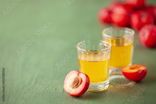 Plum brandy or plum vodka, strong drink in glasses on  table. Balkan Slivovica. Fresh red plums. Copy space photo