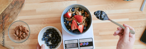Foto Hands presenting smoothie bowl with fresh fruit, nuts, and seeds on scale, surrounded by ingredients