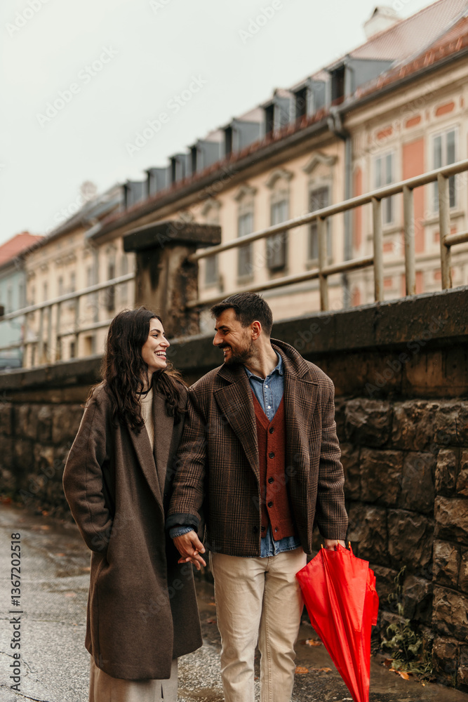 Romantic couple holding hands and walking in Prague during a rainy autumn day Romantic couple holding hands and walking in Prague during a rainy autumn day