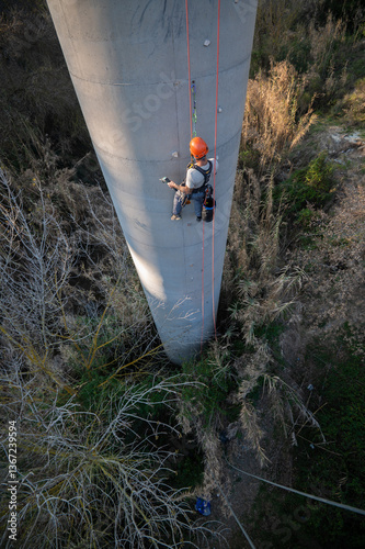 Technician inspecting concrete bridge pillar using power tool