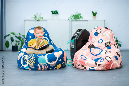 Oxygen therapy, also referred to as supplemental oxygen. Young boy with respiratory problems inhaling oxygen through nasal cannula attached to concentrator machine.