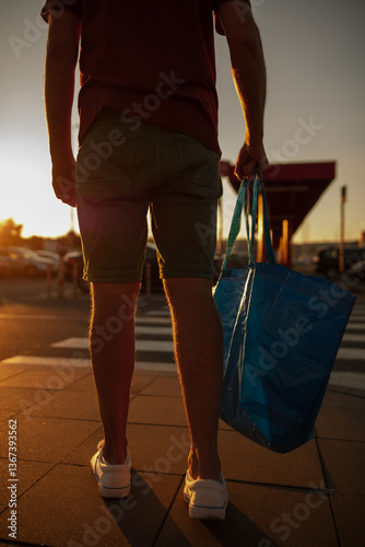 Obraz na płótnie Man with shopping bag on a market parking lot in sunset time. w salonie