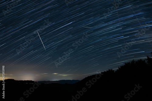 Obraz na płótnie Star trails of a Milky Way with meteor, shooting stars and landscape silhouettes. w salonie