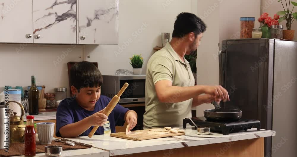  Son rolling out dough in the kitchen and father making chapati in the kitchen