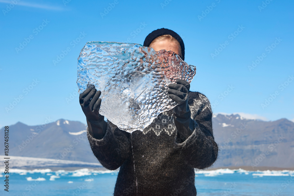 Block of ice held by a young woman. Jokulsarlon, Iceland.