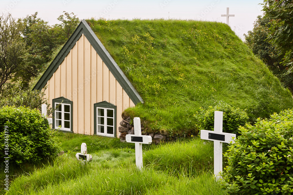 Picturesque icelandic chapel with turf roof and cemetery. Hof, Iceland