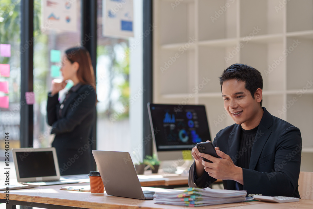 Young happy entrepreneur using a smartphone for online banking, checking emails, browsing social media, ordering food, and making video calls in a bright office Young happy entrepreneur using a smartphone for online banking, checking emails, browsing social media, ordering food, and making video calls in a bright office