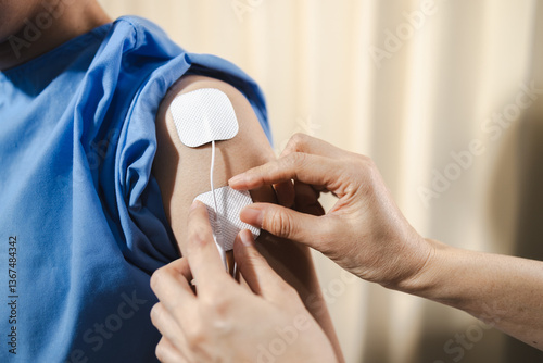 professional applies electrical stimulation pads for physical therapy on patient arm to enhance recovery and relieve pain