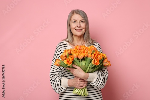 Smiling woman with bouquet of tulips on pink background