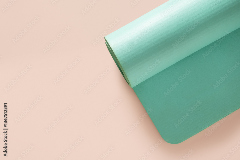 Green foam yoga mat isolated on beige background. Relaxation and meditation concept. Accessories for yoga practice. Top view. Copy space.
