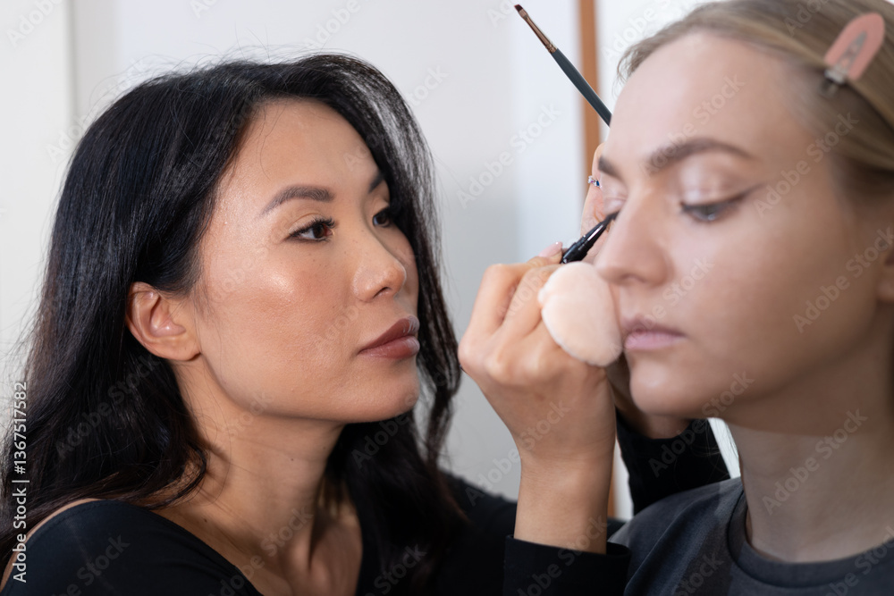 Professional makeup artist carefully applying eyeshadow to a young woman in a beauty salon. The setting is bright and modern, showcasing a beauty treatment in progress. Professional makeup artist carefully applying eyeshadow to a young woman in a beauty salon. The setting is bright and modern, showcasing a beauty treatment in progress.
