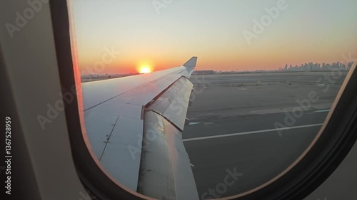 Airplane wing view landing over Doha airport at golden hour, Qatar