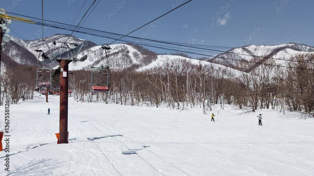 Skiers on gentle slope, trees, mountain. POV from chairlift. Hakuba Skiers on gentle slope, trees, mountain. POV from chairlift. Hakuba