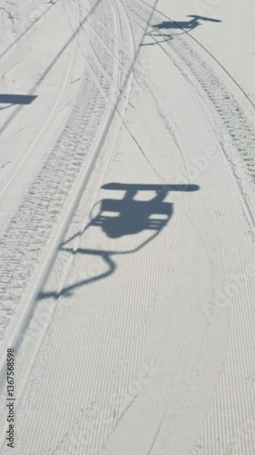 Shadow of ski lift on snow beneath. Vertical  handheld.