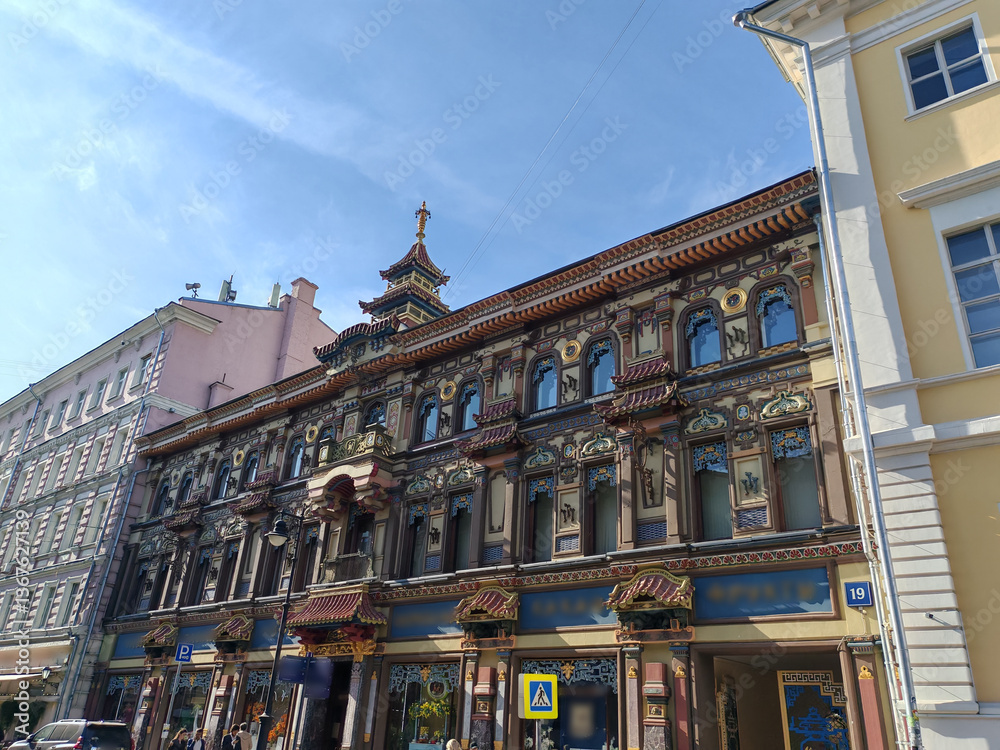 Fototapeta premium tall pink residential building with classical decorative elements, featuring numerous windows and air conditioning units. The facade reflects the charm of historic urban architecture adapted for