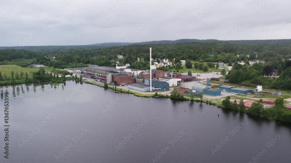 Establishing drone shot of Hafrestroms Foretagspark during the day with body of water and trees, industry in Asensbruk, Dalsland, Sweden