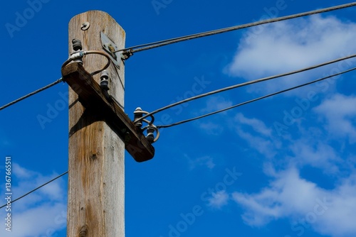 A close-up view of a power line post with numerous wires set against a blue sky