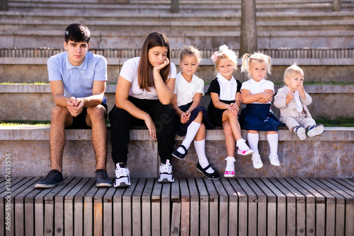 Group of Children and Teens Sitting on Bench in Outdoor Amphitheater