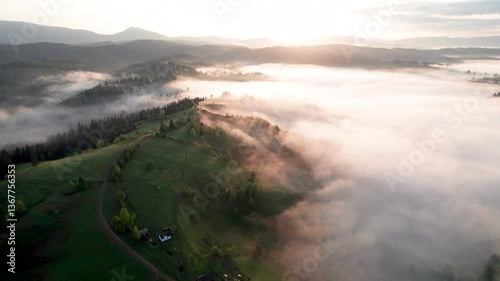 Wallpaper Mural Aerial view of sunrise over mist-covered landscape, with golden light illuminating rolling hills and valleys. Thick fog creates mystical atmosphere, partially obscuring lush greenery and trees below. Torontodigital.ca