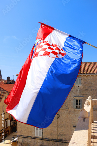 Croatian flag blowing in the wind on the bell tower of The Cathedral of St. Lawrence, landmark in Trogir, Croatia.