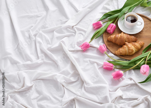 A warm, heartfelt Mother’s Day surprise featuring croissants, a cup of coffee, and fresh pink tulips arranged on cozy white linens.