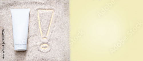 Importance of skin health, UV protection. Protection sunscreen (sun cream) bottles on sand. Exclamation mark drawing near bottle on the sand background. Sun tan, summer skin care. Copy space. 