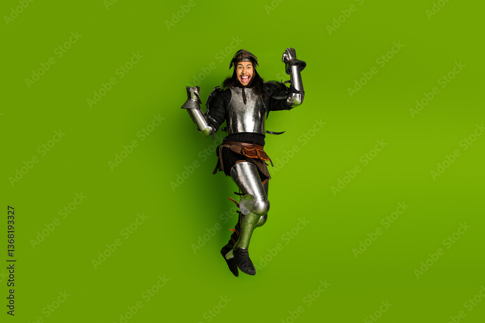 Obraz premium Portrait of a young knight in full armor expressing joy on a green background