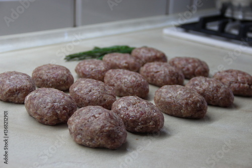 Homemade meatballs of pork and beef, arranged in lines on the table chili pepper and rosemary