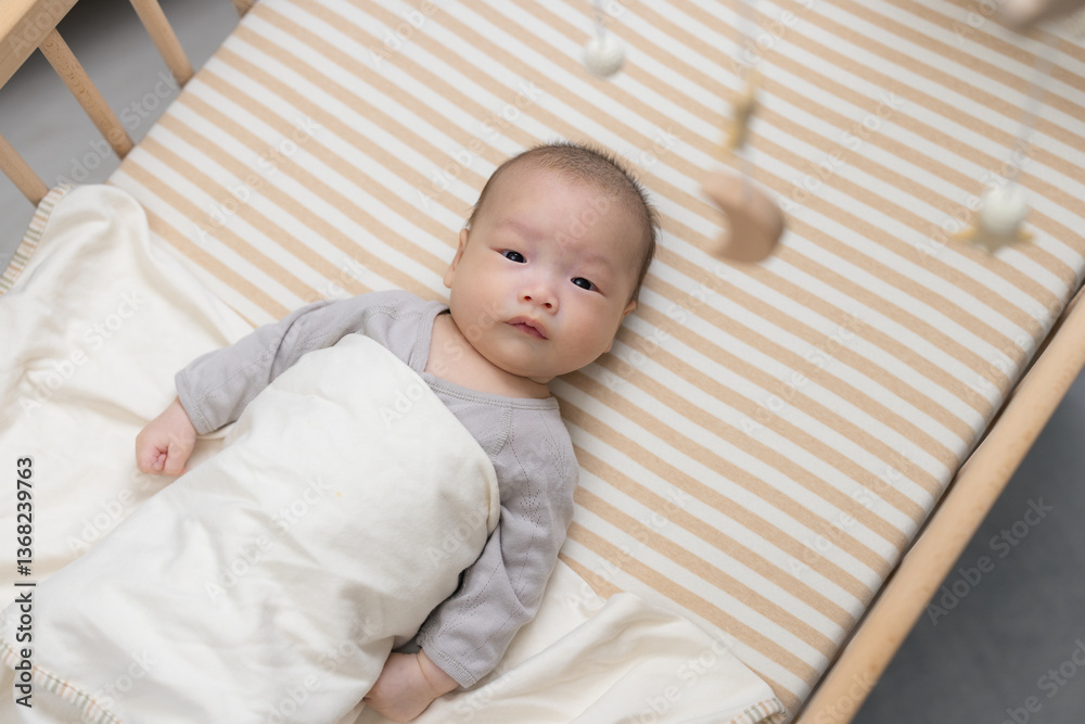 Curious baby looking at hanging toy in crib