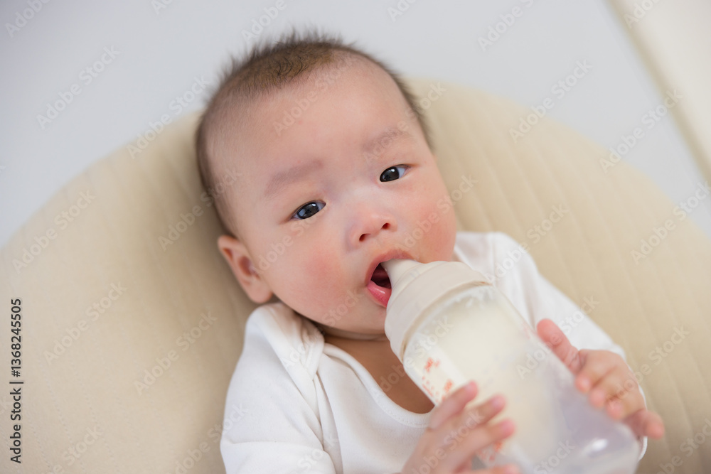 Infant holding bottle while drinking fresh milk