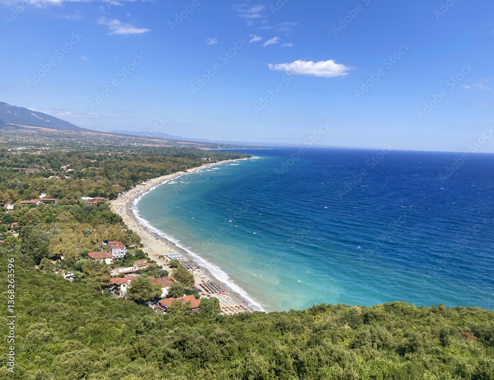Aerial view of a Mediterranean, Caribbean style coastline in Greece, a tranquil sandy beach, turquoise sea, and lush green forest. Clear blue skies, gentle waves, distant mountains, perfect vacation.