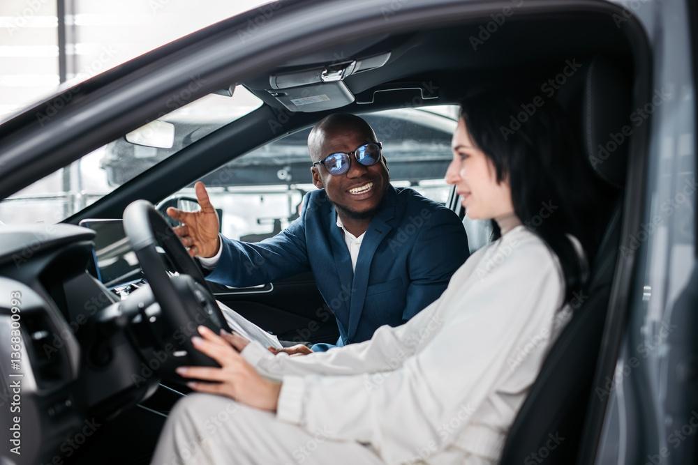 Fototapeta premium African-American dealer counseling a customer on buying a modern car at a car dealership. Concept of buying, leasing, test driving a new modern car. 