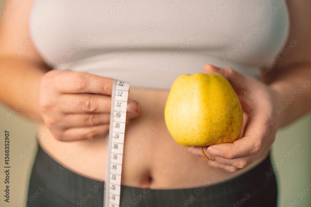A woman holding a yellow apple in one hand and a measuring tape in the other, symbolizing healthy eating, wellness, and weight control. Concept of dieting, body care, and balanced nutrition