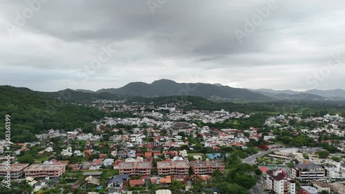 View of a vibrant hillside town under cloudy skies with mountains in background