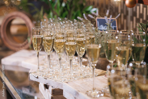 On the table, there are many glasses filled with champagne waiting