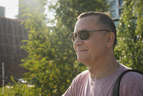 Obraz na płótnie Portrait of smiling adult man wearing sunglasses and pink t-shirt at summer park. Outdoors. Close up. w salonie