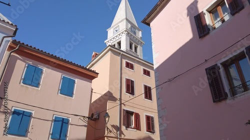 Bell tower of St Martin church appearing above the roofs of the colorful buildings of old town Vrsar, Croatia