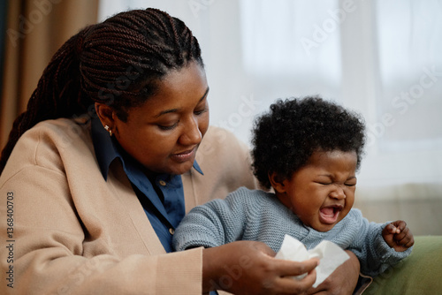 Medium shot of caring Black mother comforting restless little daughter giving good cry while sitting together on couch at home