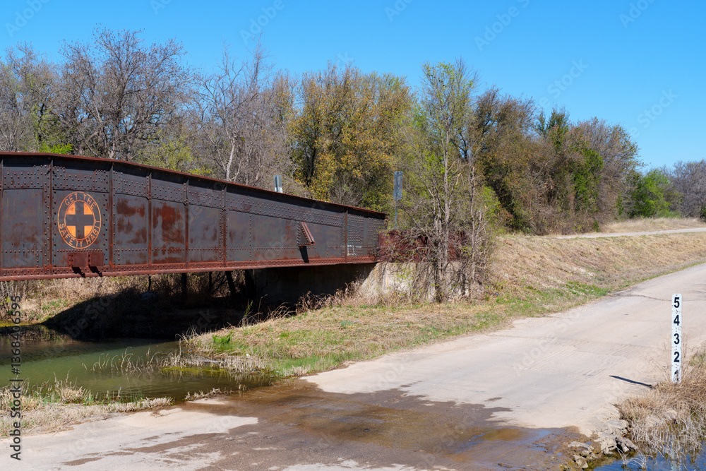 Obraz premium Rusty, old rail bridge used to span a creek in oil field area in West Texas. Now only used when needed by motor vehicles and pedestians.
