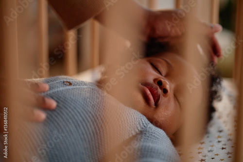Konstfotografi Shot through wooden crib slats of Black baby girl peacefully sleeping in bed whi