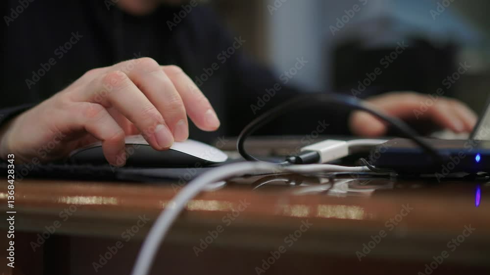 Closeup of a Hand on a Mouse While Effectively Working on a Laptop in a Modern Office Closeup of a Hand on a Mouse While Effectively Working on a Laptop in a Modern Office